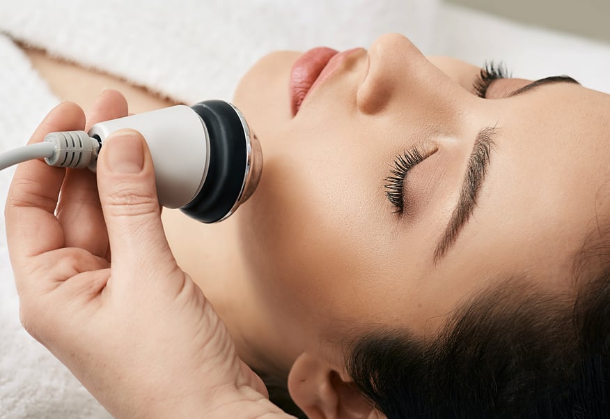 Brunette woman receiving radiofrequency lifting procedure for her face skin rejuvenation at aesthetic cosmetology clinic